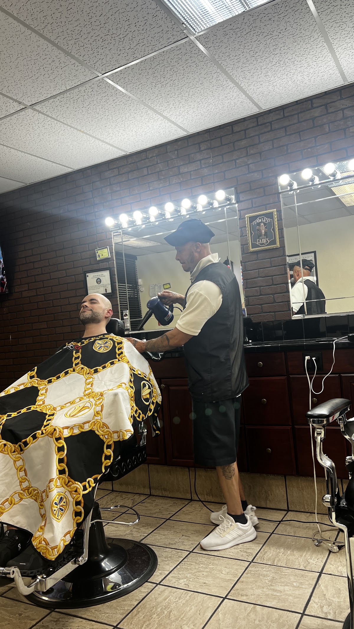 Barber finishing a client's cut under bright mirror lights